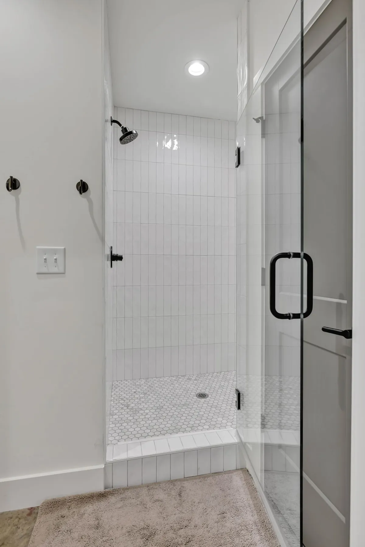 A modern bathroom with a glass shower enclosure, hexagonal tile flooring, and a sleek showerhead. The design feels both refreshing and serene, inviting relaxation and self-care.
